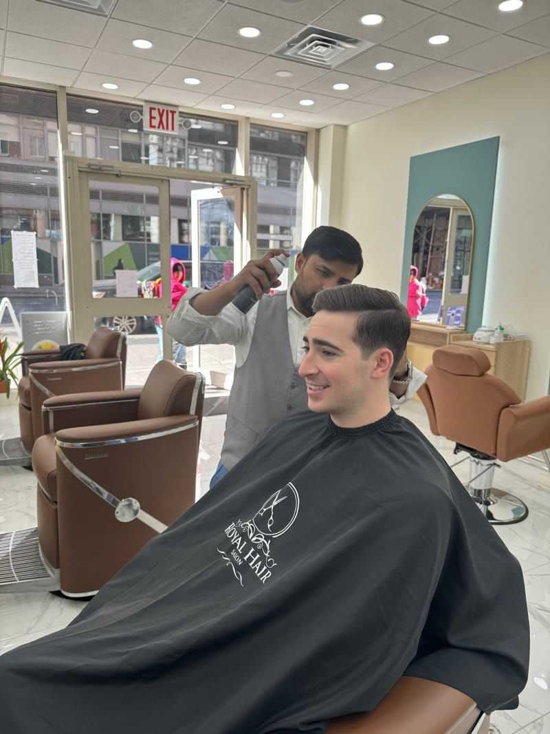 Man getting a haircut in a modern salon with stylist using scissors.
